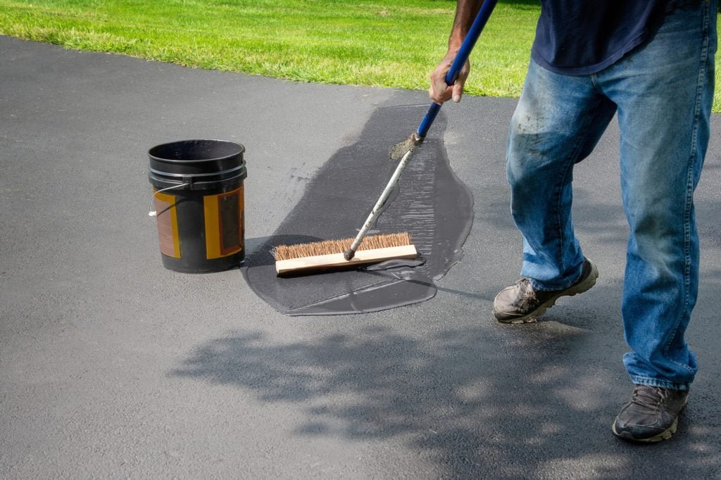 Homeowner Spreads Blacktop Asphalt Sealant On Driveway Homeowner Spreads Blacktop Asphalt Sealant On Driveway